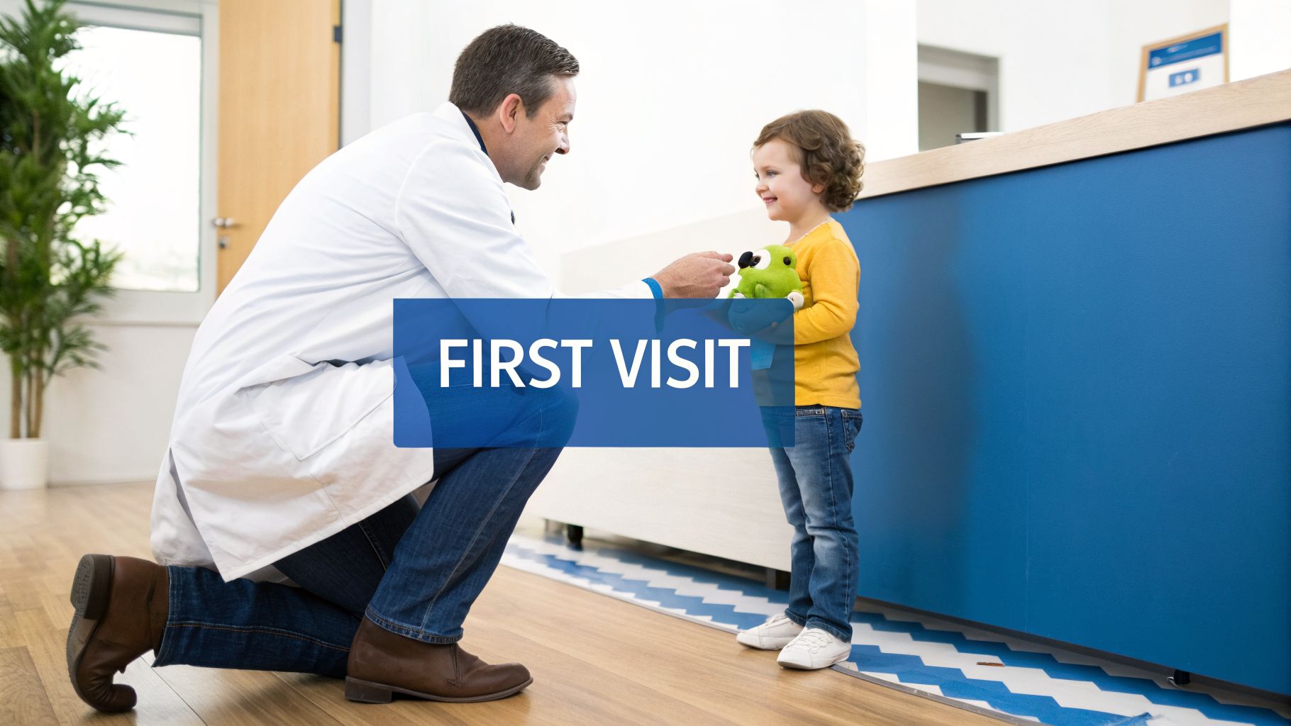 A friendly male doctor kneels to greet a smiling young girl holding a green frog toy during her first visit.